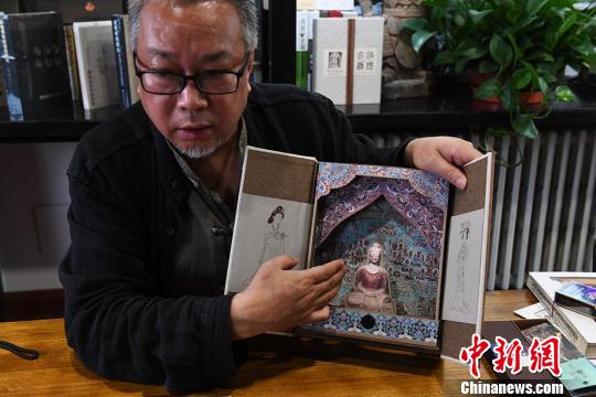 從函盒下方抽出藏書票筆記本時，佛陀身后的畫面由原先莫高窟第454窟《梵網經變圖》變化成第148窟《藥師經變圖》。　楊艷敏 攝
